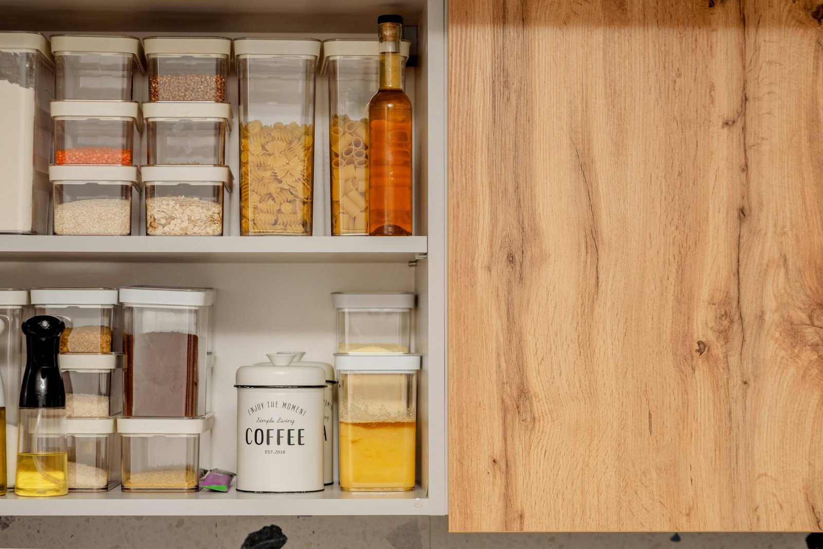 Kitchen pantry cabinet with clear containers of pasta, grains and coffee neatly organized