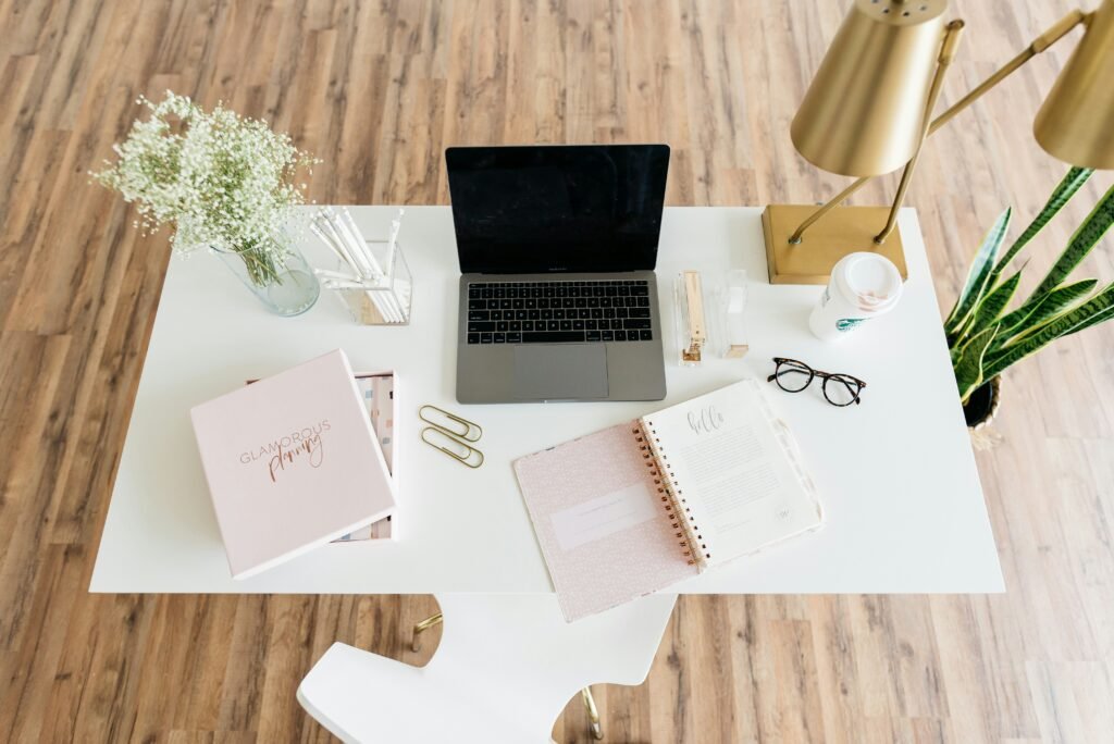 Tidy desk flatlay with an open planner, laptop, coffee and glasses for planning the day