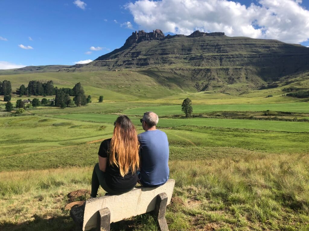 Couple sitting on a bench looking out over the Drakensberg mountains in South Africa
